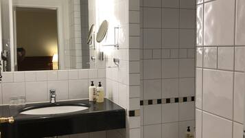 A bathroom with a black countertop sink, a mirror, two soap dispensers, a stool, and a towel rack.