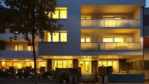 Un hotel de diseño moderno, con una entrada destacada, zona de estar al aire libre y varios balcones.