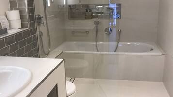 A modern bathroom with a glass-enclosed shower, a standalone bathtub, and a vanity with a sink.