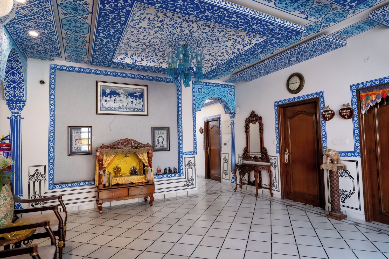 A room with a tiled floor, blue and white patterned walls, a wooden chair, a wooden cabinet, and a mirror.