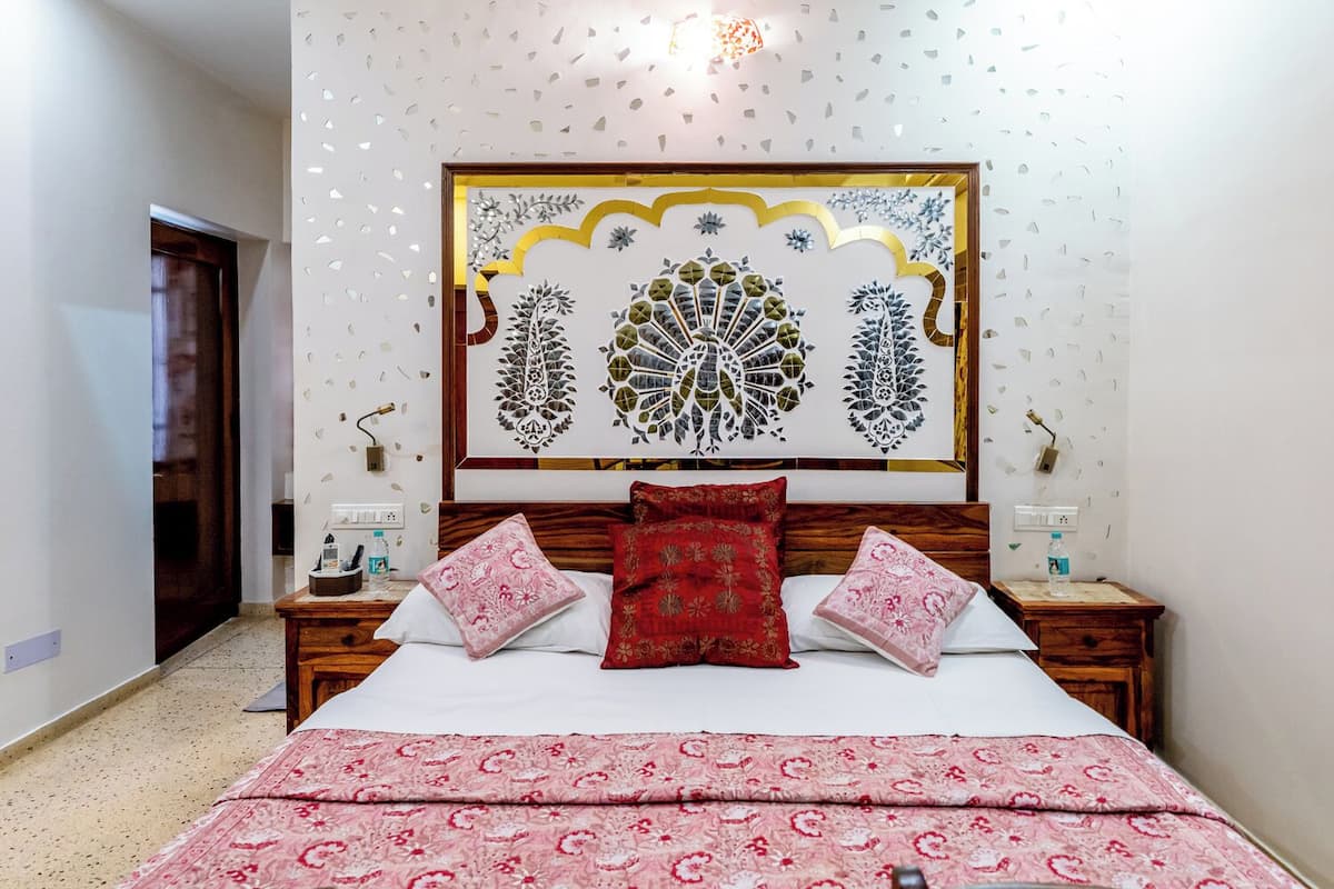 A bedroom with a bed, two nightstands, a decorative wall piece, and a door.