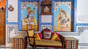 Una habitación tradicional con sofá, cojines y dos cuadros enmarcados.