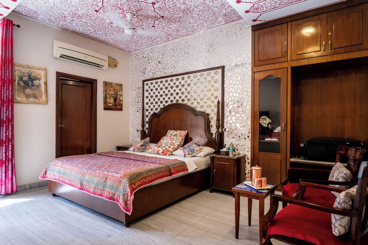 A bedroom with a wooden bed, a nightstand, a red chair, and a wardrobe.