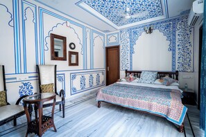 A bedroom with a bed, a chair, a mirror, and a door. - All Seasons Heritage Homestay (Jaipur)