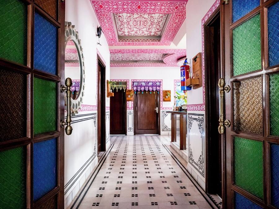 A hallway with patterned doors and a tiled floor, leading to a room with a door and a small table.
