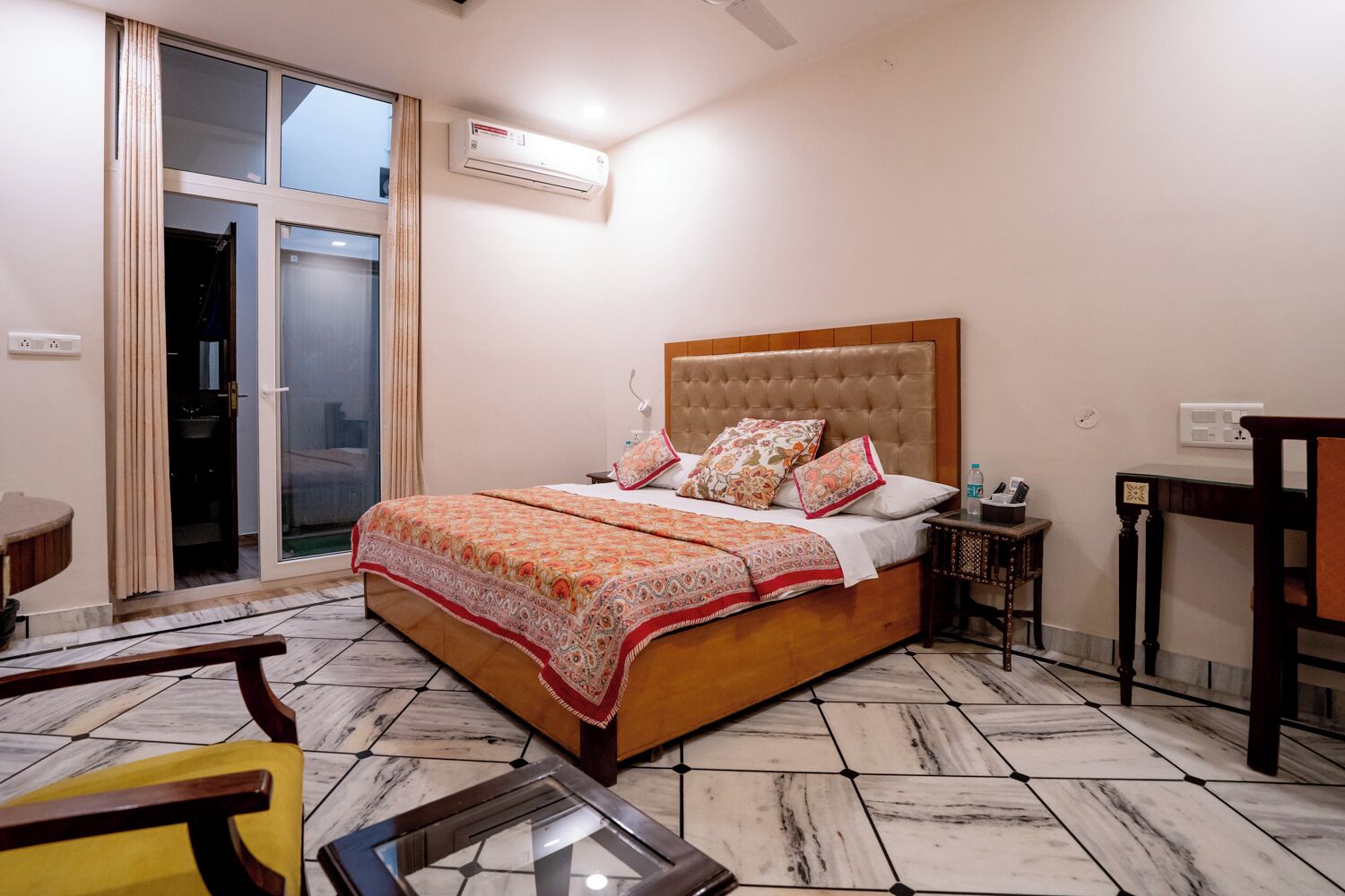 A bedroom with a bed, a bedside table, a chair, and a window with curtains.