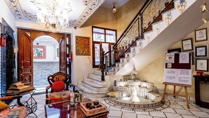 Un lobby espacioso con una escalera de mármol, una fuente y una zona de estar con una silla roja.