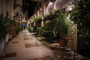 A corridor lined with potted plants and a checkered floor, leading to a staircase. - All Seasons Heritage Homestay (Jaipur)