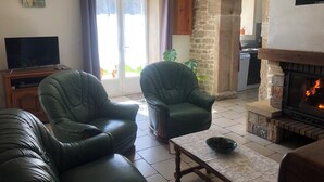 Een woonkamer met leren banken, een televisie, een open haard en een stenen muur.