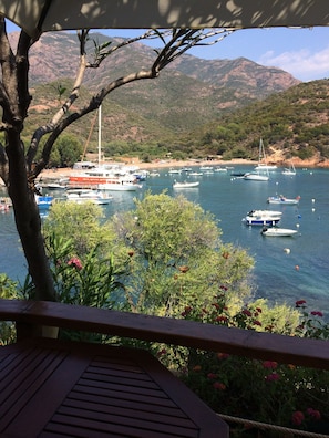 A coastal view with boats docked, a beach, and mountains in the background.