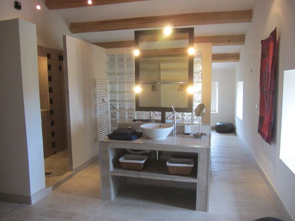 A bathroom with a large mirror, a vessel sink, and built-in shelves.