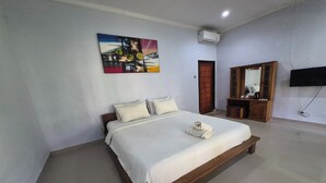 Ein Schlafzimmer mit Bett, Gemälde, Fernseher und Spiegel.