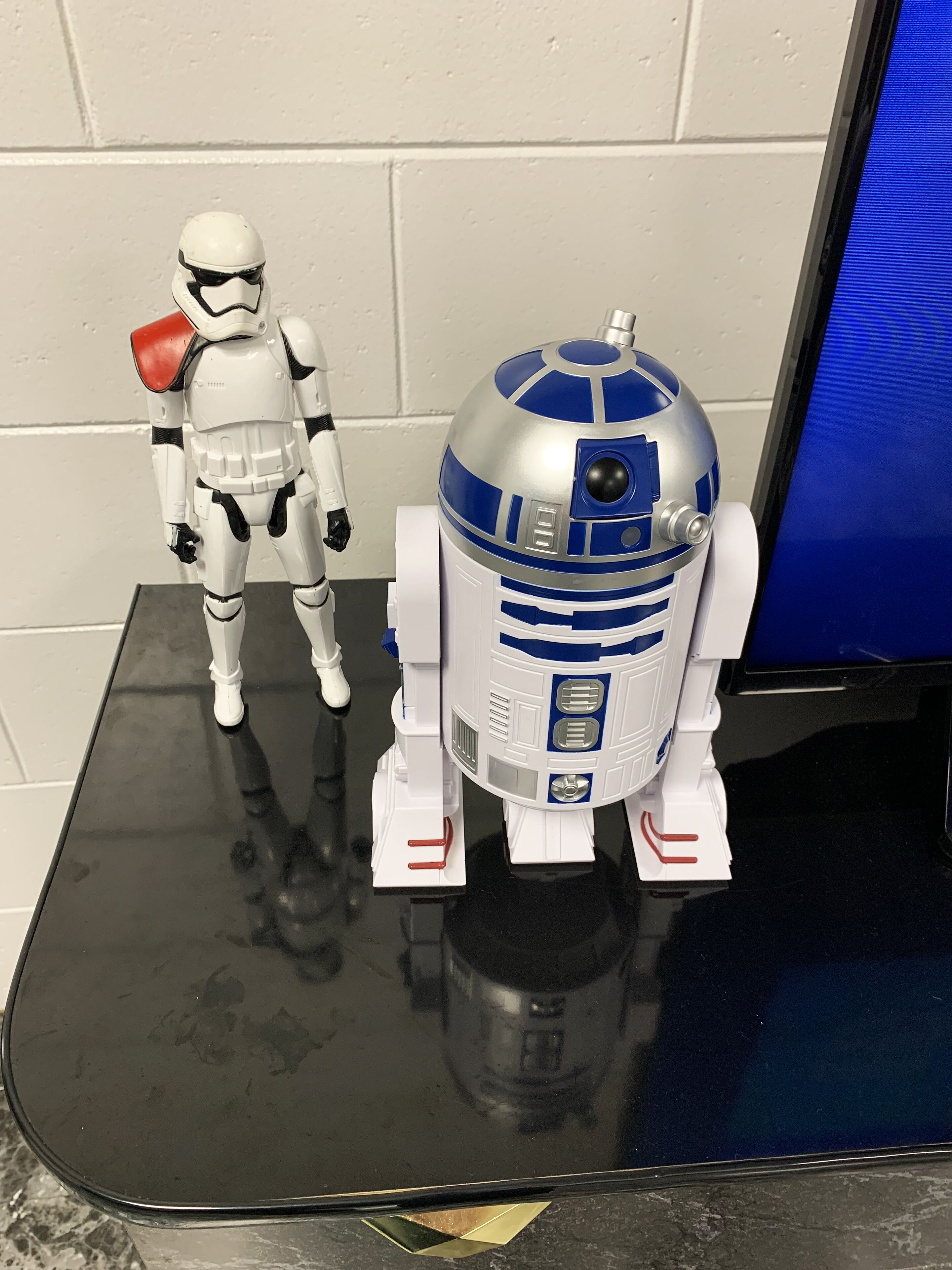 Une figurine d’action de Star Wars et un droïde sur une surface réfléchissante.