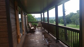 A wooden porch with a view of a green landscape.