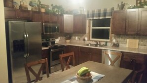 A kitchen with wooden cabinets, stainless steel appliances, and a dining table with chairs.
