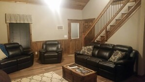 A living room with two leather sofas, a wooden coffee table, and a staircase.