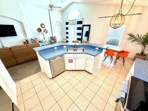 A modern kitchen with a corner island, white cabinetry, and a built-in dishwasher.