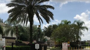 A gated entrance with palm trees, a sign for Highgate, and caution signs for speed ramps and a tow-away zone. - Perfect Vacation Getaway-Modern Gated Community, Spacious, Pool, Game Room, WiFi (Davenport)