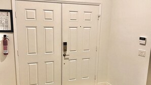A hallway with a patterned rug, double doors, a fire extinguisher, and a thermostat on the wall. - Perfect Vacation Getaway-Modern Gated Community, Spacious, Pool, Game Room, WiFi (Davenport)