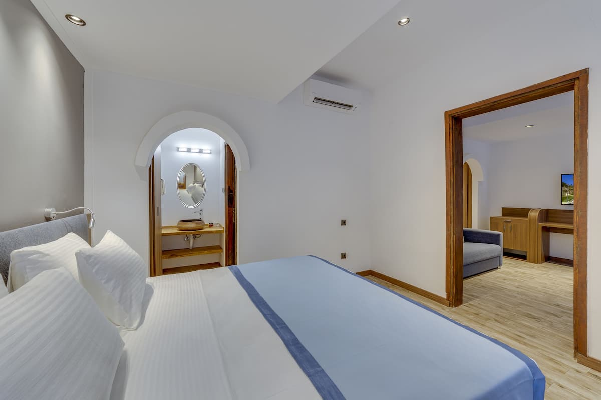 A bedroom with a large bed, a wooden desk, and a mirror.