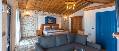 Un dormitorio con una cama, un sofá, una pared de piedra y una puerta azul.
