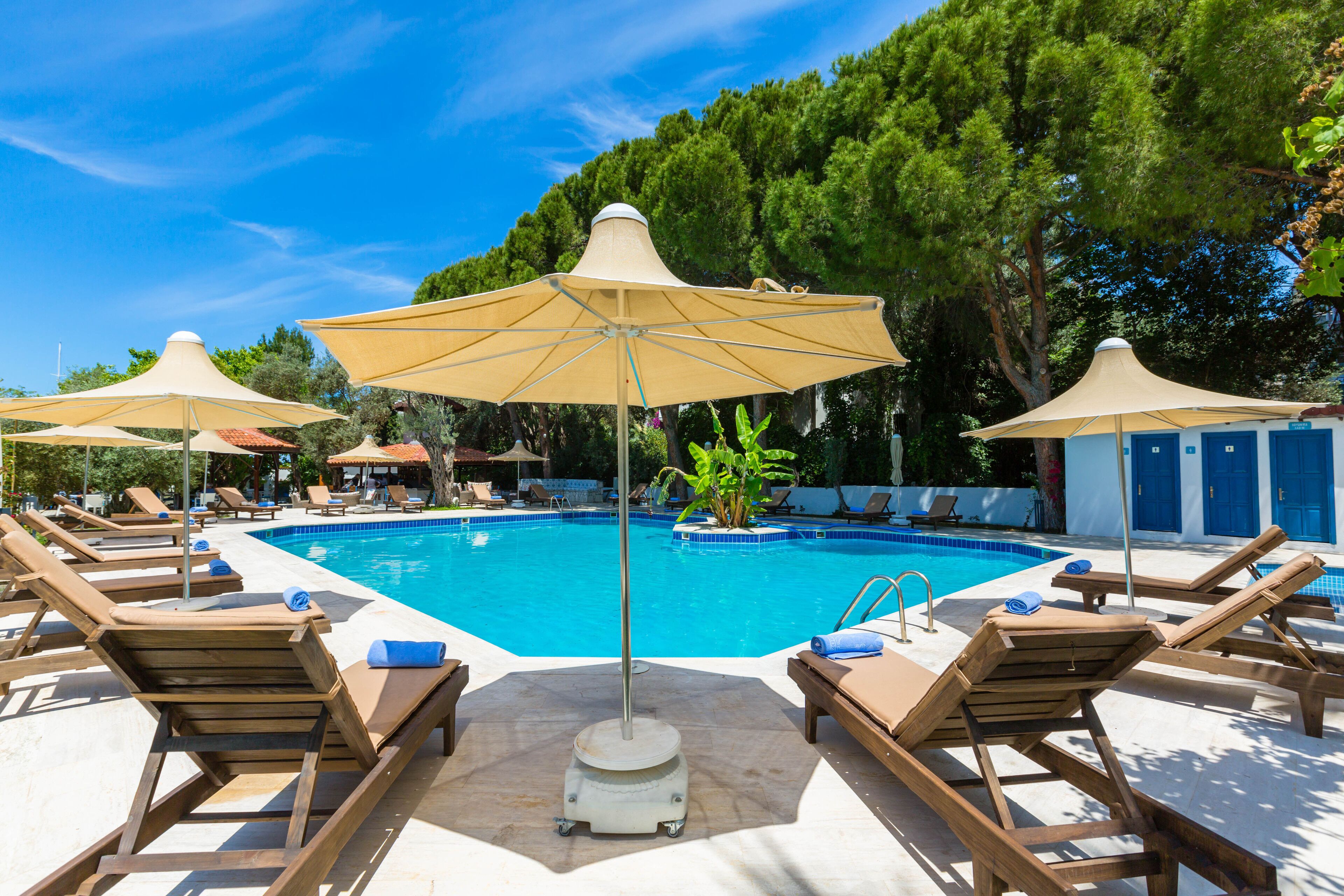 Un espace piscine équipé de chaises longues et de parasols.