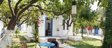 Un patio con una mesa y sillas, un banco y un edificio con una puerta azul.