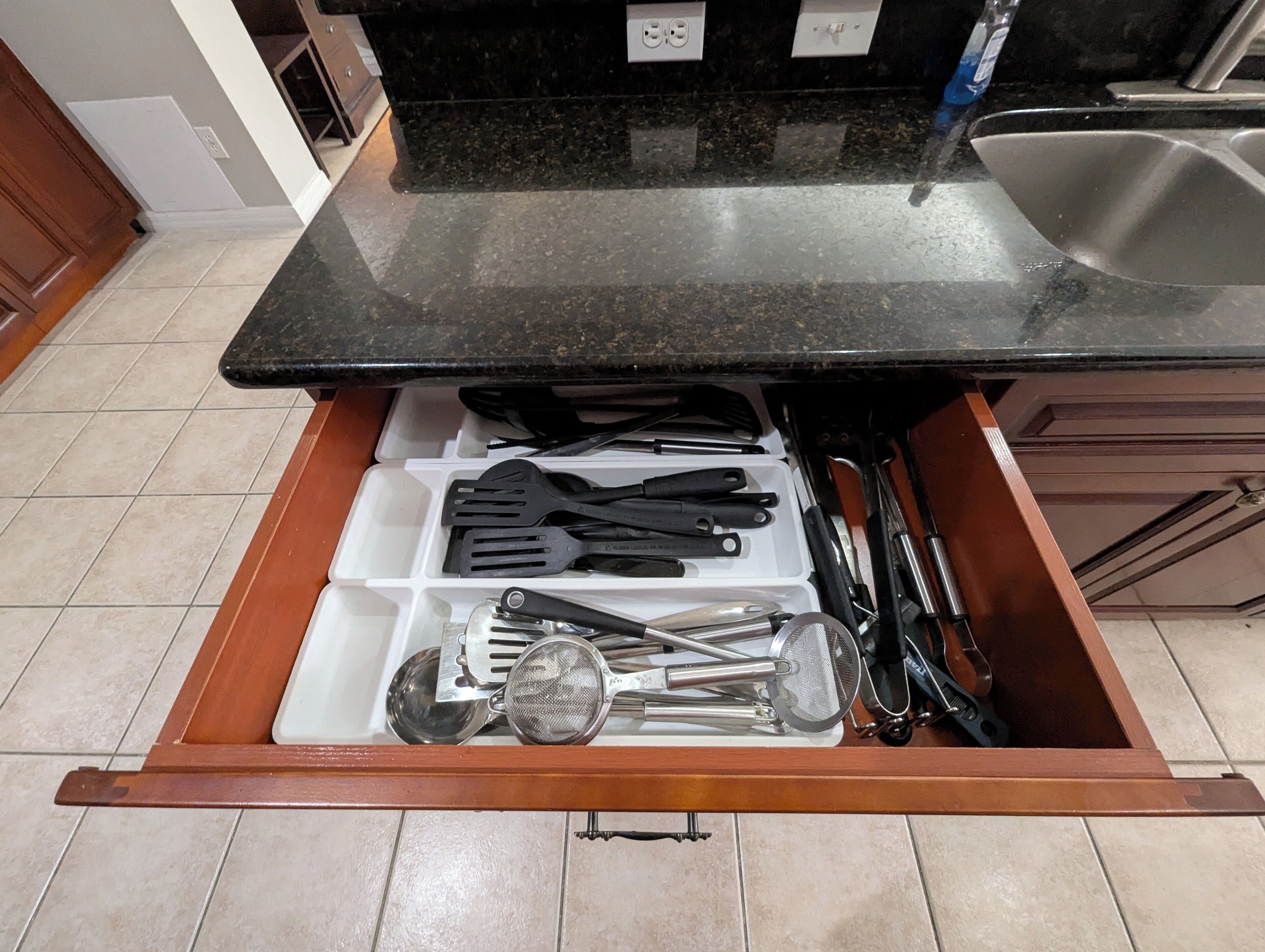 A kitchen drawer with various utensils and kitchen tools.