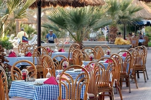 An outdoor dining area with wicker chairs and tables covered with blue and white checkered tablecloths.