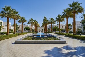 A courtyard with a central water feature, surrounded by palm trees and modern buildings. - Maritim Jolie Ville Resort & Casino (SHARM EL SHEIK)