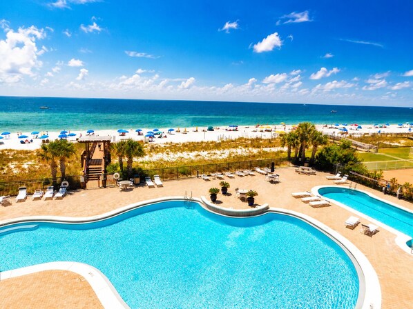 A resort with a large pool, lounge chairs, and a beach area with umbrellas. - 204 Palacio, low floor professionally decorated gulf front condo! (Pensacola)