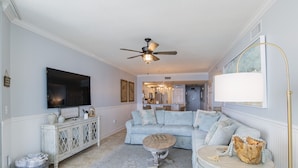 A living room with a sectional sofa, a coffee table, a TV, and a ceiling fan. - 204 Palacio, low floor professionally decorated gulf front condo!  (Pensacola)