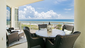 A balcony with wicker furniture, a round table, and a view of the ocean. - 204 Palacio, low floor professionally decorated gulf front condo!  (Pensacola)