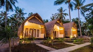 Un resort con cottage a tetto di paglia, vialetti lastricati e vegetazione tropicale.