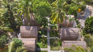 Un resort con costruzioni a tetto di paglia, palme e un viale lastricato.