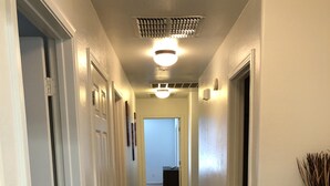 Un couloir avec un sol carrelé, des murs blancs et un luminaire au plafond.