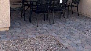 Une terrasse extérieure avec une table et des chaises, une petite fenêtre et une porte.