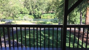 A covered outdoor area with a wooden deck and a view of a landscaped garden and a pond.