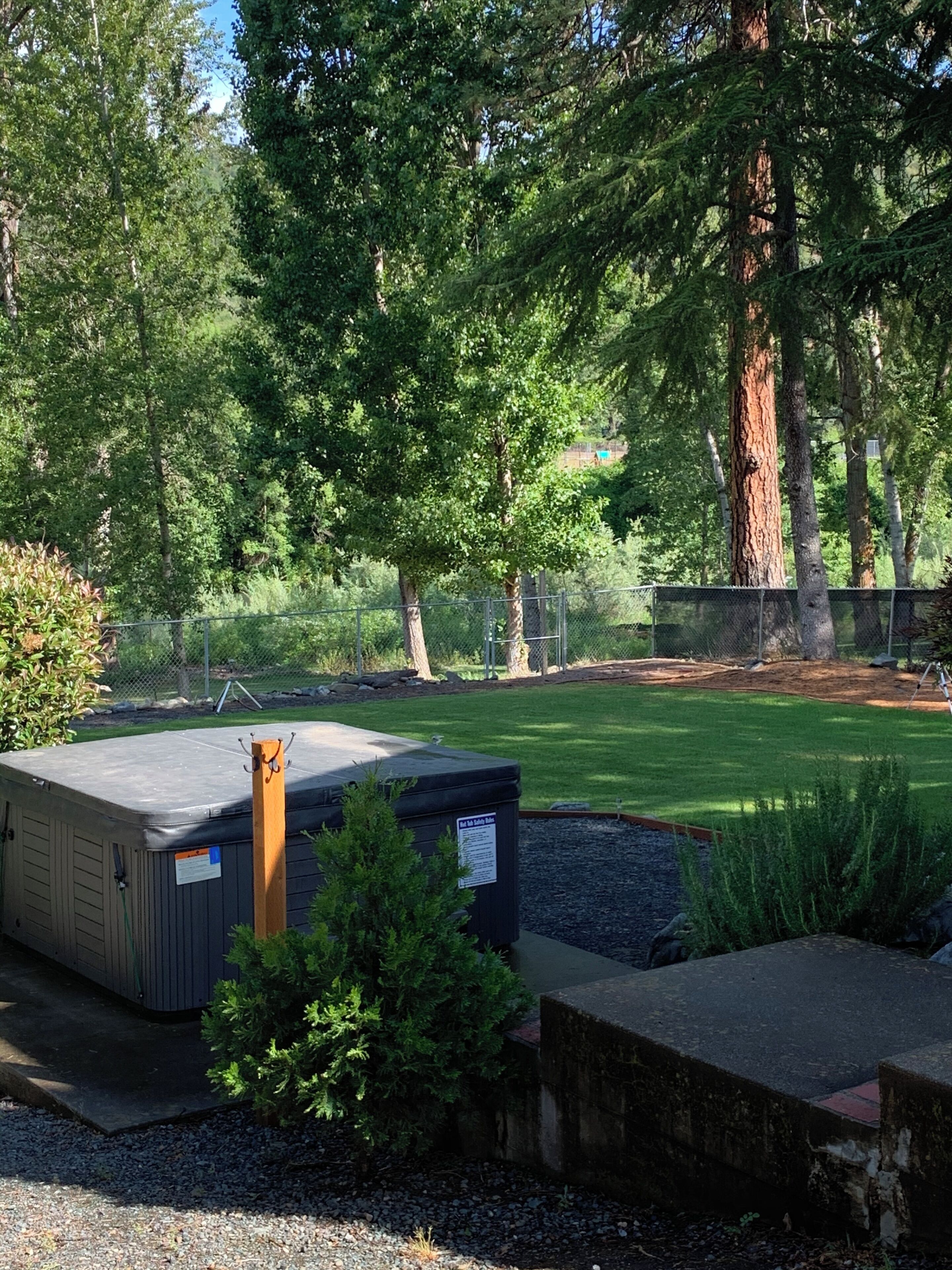 A well-maintained outdoor area with a large tree, a fenced play area, and a small building with a sign.