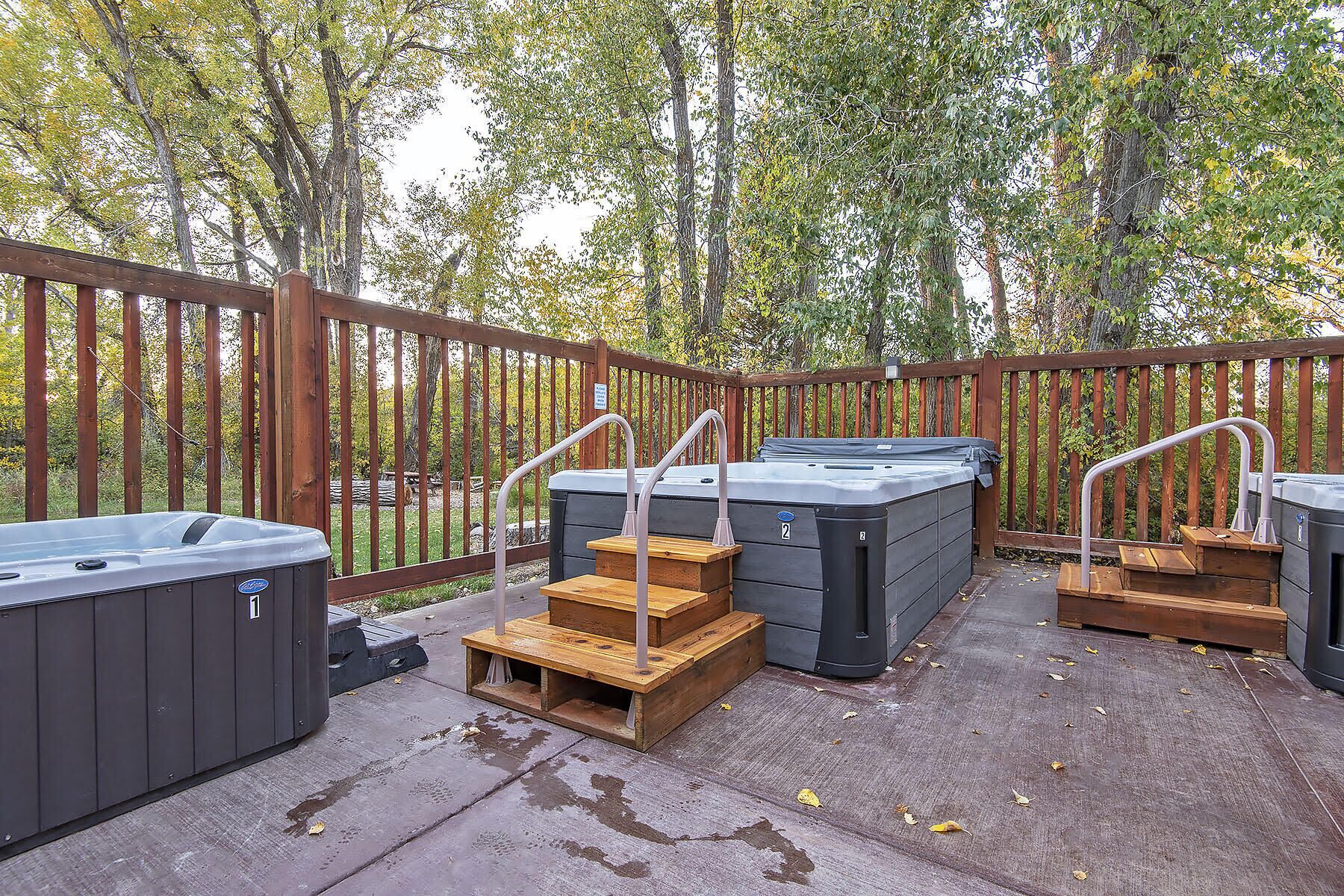 A deck with hot tubs and wooden steps.