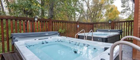 Two hot tubs on a wooden deck with a wooden fence in the background.