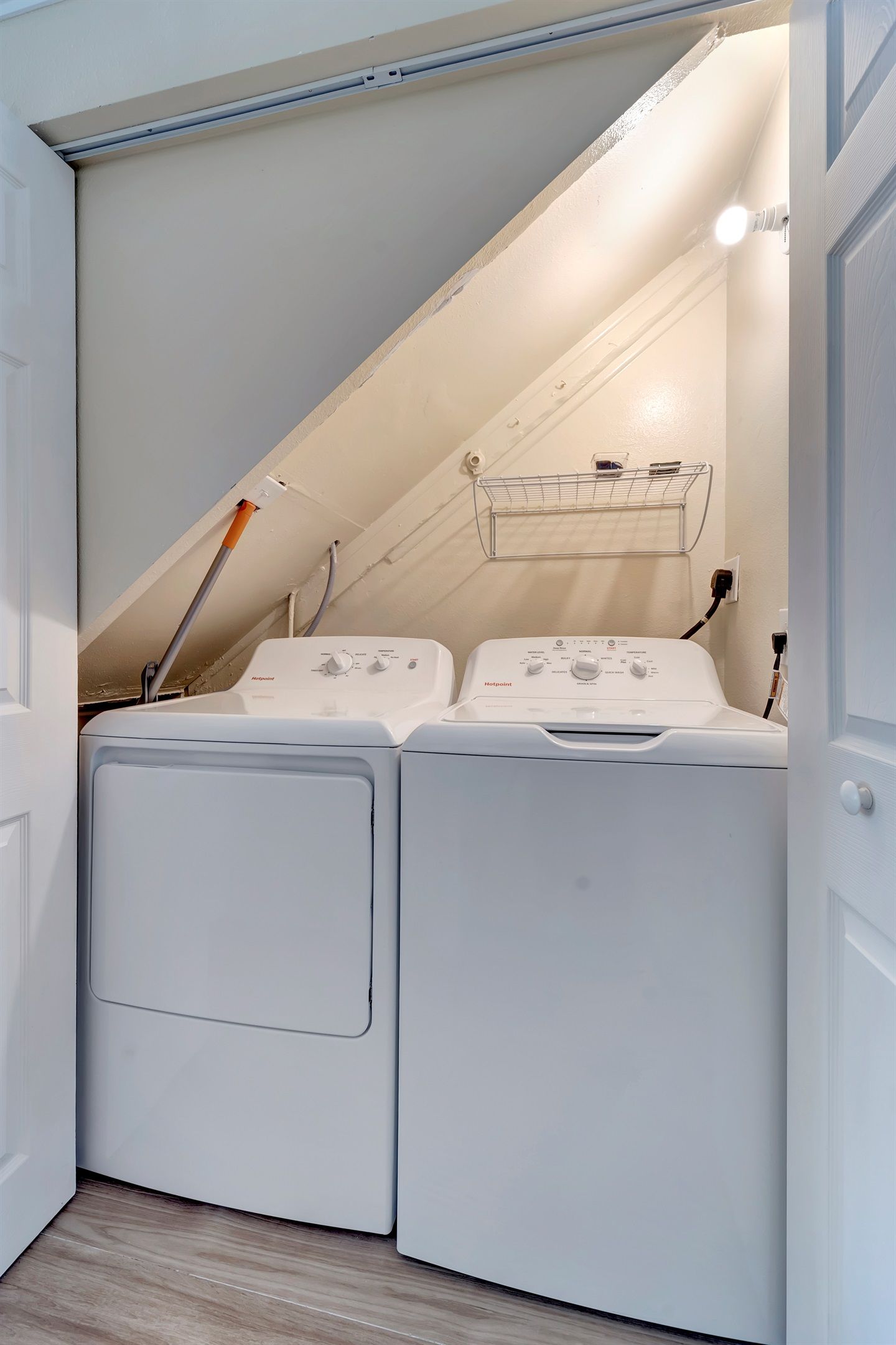 A laundry room with two white front-loading washing machines and a metal drying rack.