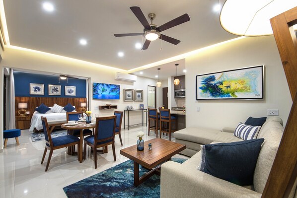 A modern hotel room with a dining area, a sofa, a TV, and artwork on the walls. - Ocean view apartment Zona Romantica with amazing rooftop pool and terrace! (Puerto Vallarta)