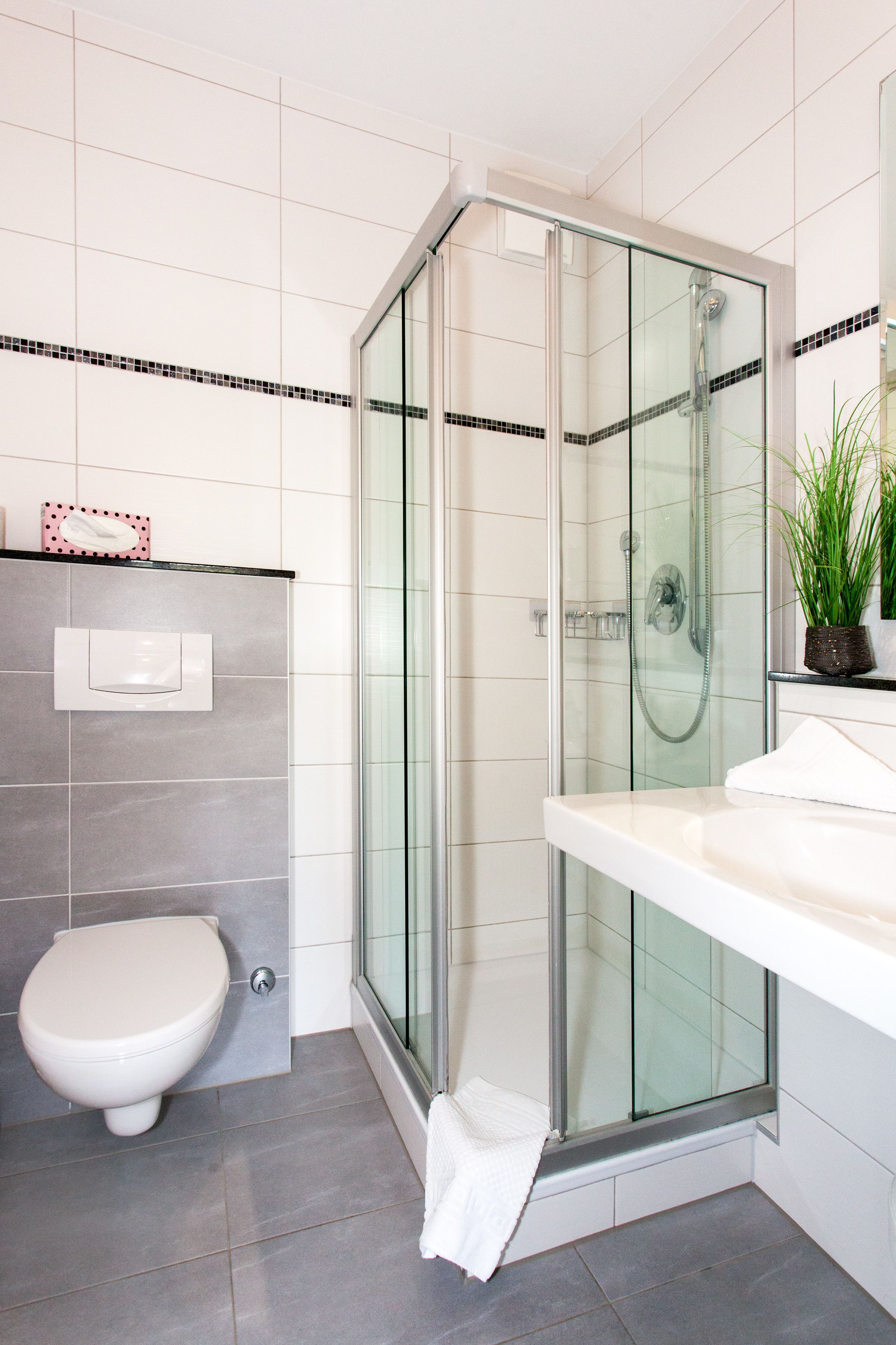 Un baño moderno con ducha de vidrio, inodoro y lavamanos con toalla.
