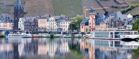 A riverside town with historic buildings, a church tower, and a bridge.