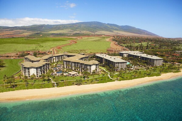 A beachfront hotel with multiple buildings, a sandy beach, and a clear view of the ocean.
