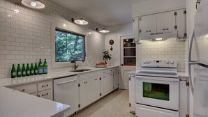 A modern kitchen with white cabinetry, a large window, and a built-in oven.
