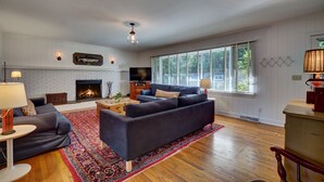 A spacious living room with a fireplace, large windows, and a cozy seating area.