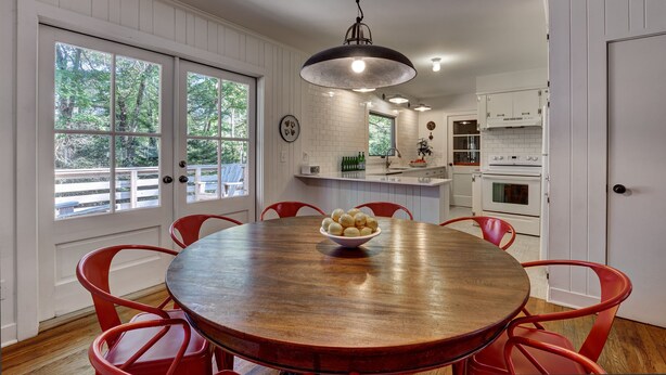 A kitchen with a round wooden table, red chairs, and a bowl of fruit.