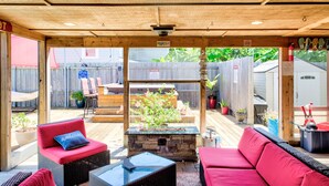A covered patio area with wicker furniture, a stone table, and a fire pit.
